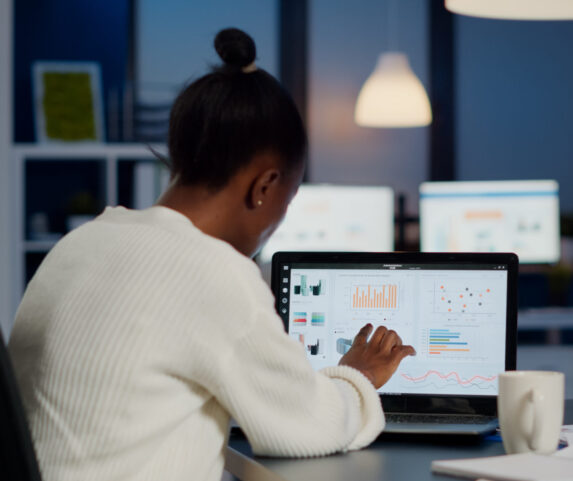 Black manager checking business statistics and financial reports on laptop